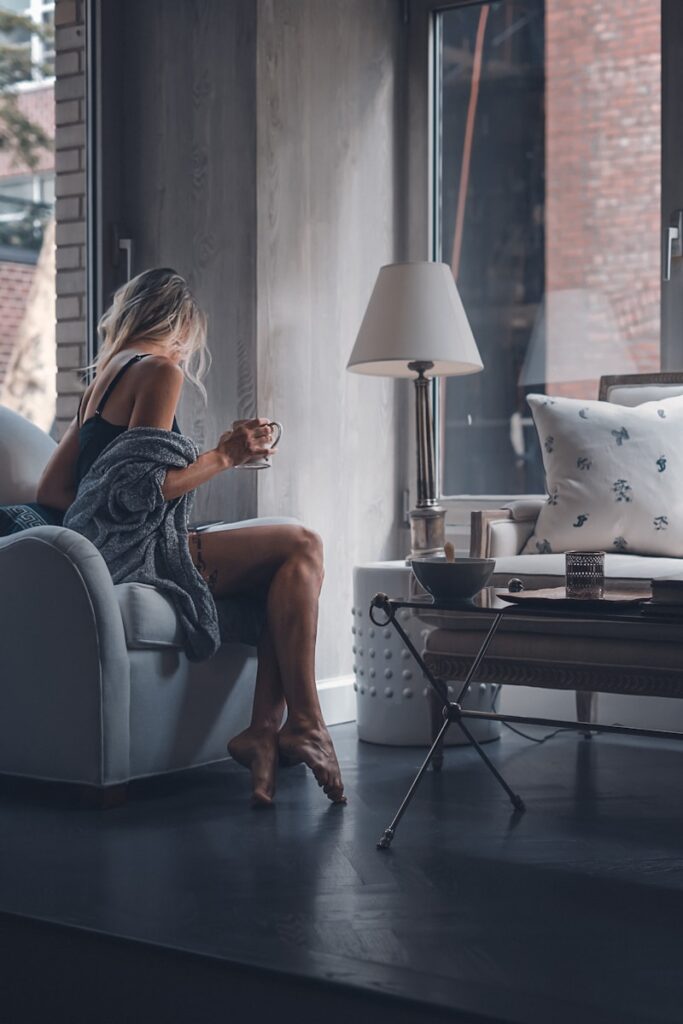 Photo by Toa Heftiba woman sitting on gray sofa chair holding mug